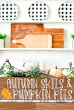 Decorative shelf with autumn-themed items including a wooden sign, pumpkins, and checkered plates.