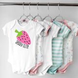 Collection of baby onesies on hangers with various designs including a strawberry graphic.