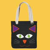 Black tote bag with cat face design on a yellow background