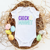 White baby onesie with 'CHICK MAGNET' text on a nest with colorful eggs