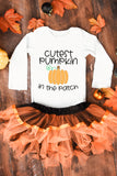 Children's outfit with 'Cutest Pumpkin in the Patch' text on a wooden background with fall leaves and pumpkins.