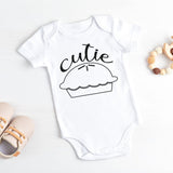 White baby onesie with 'cutie pie' design on a light background
