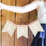 Person holding a 'EAT' banner against a wooden background