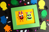 Two colorful monsters in a green frame surrounded by various monster shapes on a black background