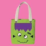 Green tote bag with a cartoonish monster face on a pink background