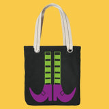 Black Halloween tote bag with green and black witches legs and purple shoes on a yellow background